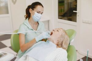 Imagen de una mujer mayor con la boca abierta teniendo una revisión bucal en el dentista.