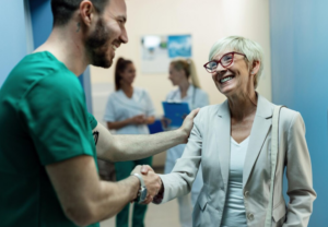 imagen de un médico y una mujer mayor dándose la mano en una sala de espera