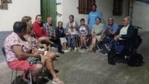 Imagen de un grupo de personas sentadas en sillas en la calle hablando en corrillo