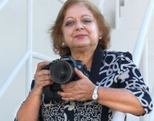 Imagen de Cristina García, sonriente con una cámara fotográfica entre las manos.