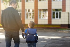 Abuelo y un niño agarrados de la mano entrando en el colegio