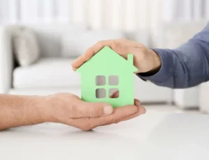 Dos manos sosteniendo un casa pequeña