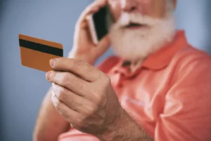 Hombre mayor hablando por telefono con tarjeta banco en mano