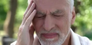 Imagen de hombre mayor dolorido con ojos cerrados y mano en cabeza