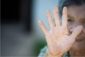 Mano de mujer mayor tapando la cara