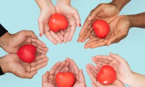 Manos juntas con corazones rojos