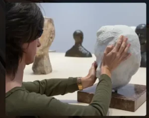 Mujer discapacidad visual tocando escultura