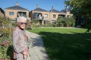 Mujer mayor con gafas de sol en patio rodeado de varias casa cohousing