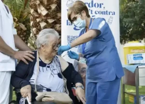Mujer mayor en silla siendo vacunada por la covid