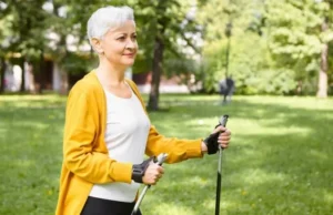 Mujer mayor paseando con bastones por parque