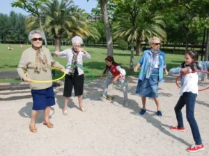 Mujeres mayore y niñas bailando el aro al aire libre