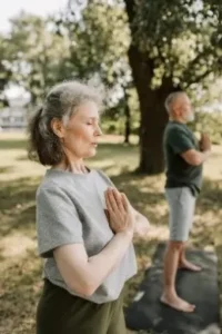 Pareja mayor de pie postura yoga aire libre