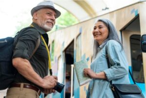 Pareja de personas mayores sonrientes subiendo a un tren