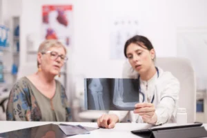 Persona mayor en consulta medica mirando radiografía