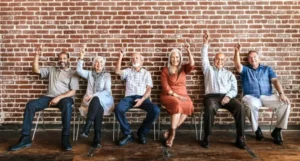 Personas mayores sentadas en silla levantando mano