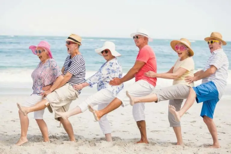 Personas mayores sonrientes haciendo la conga en la playa