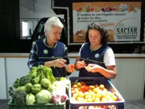 Dos mujeres mayores vendiendo fruta en un puesto en la calle