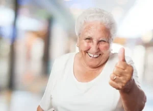 Mujer mayor sonriente con dedo pular levantado