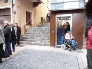 Persona con dicapacidad fisica en silla de ruedas saliendo de una ascensor salvaescalera