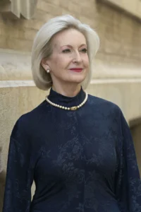 Mª Trinidad Herrero con sonriente vestido azul y colar de perlas
