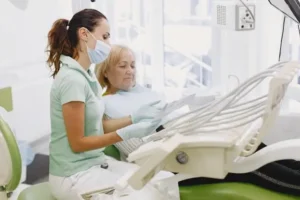 Mujer mayor sentada en sillón dental escuchando las explicaciones de la dentista