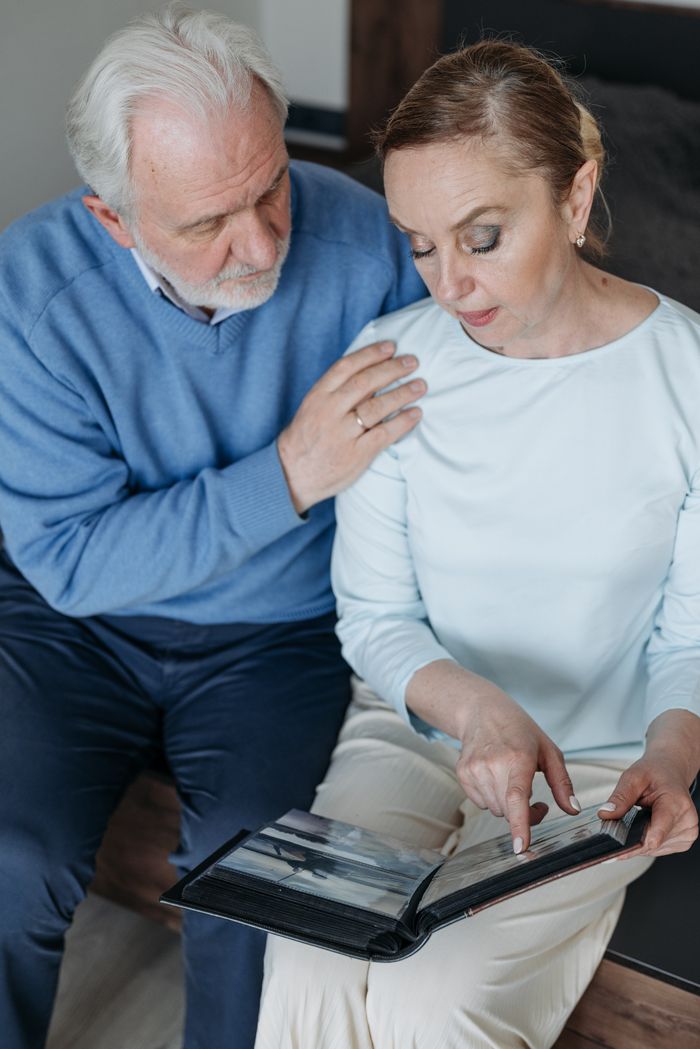 Senior couple sharing memories while looking through a photo album indoors.