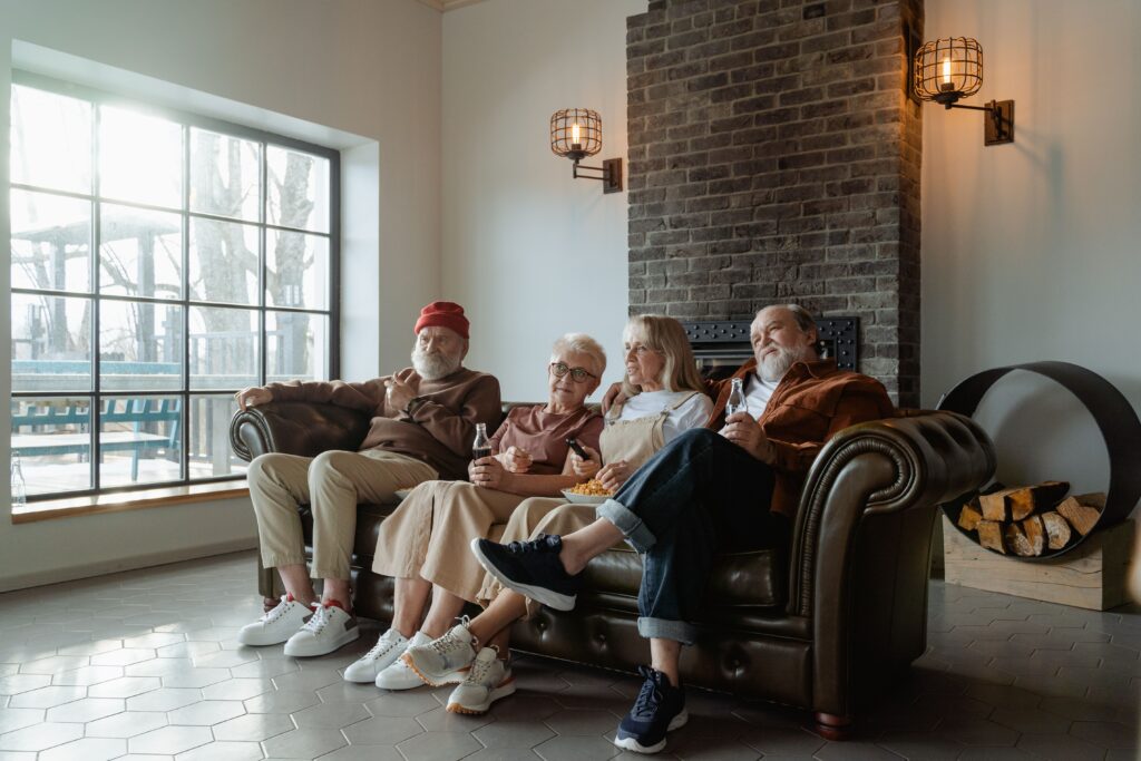 A group of senior adults relaxing comfortably indoors on a sofa, enjoying a leisurely moment.