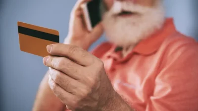 Hombre mayor hablando por telefono con tarjeta banco en mano