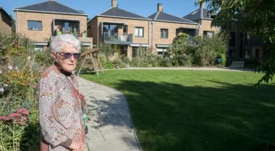 Mujer mayor con gafas de sol en patio rodeado de varias casa cohousing